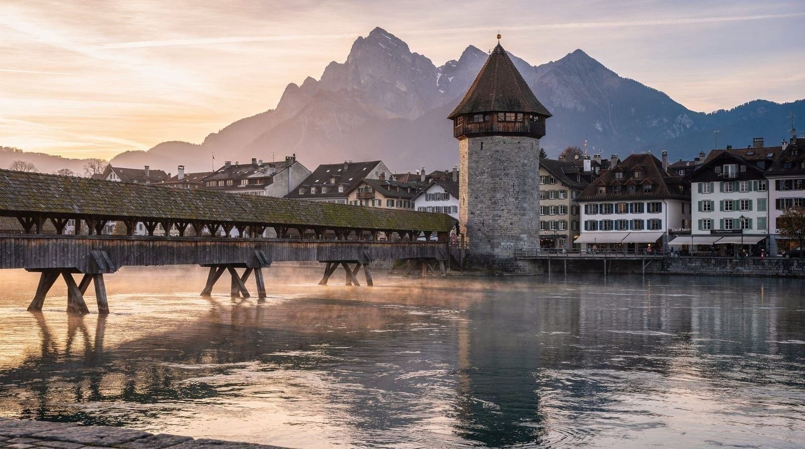 El casco antiguo de Lucerna y el puente de la Capilla al atardecer, con los Alpes visibles en el horizonte.